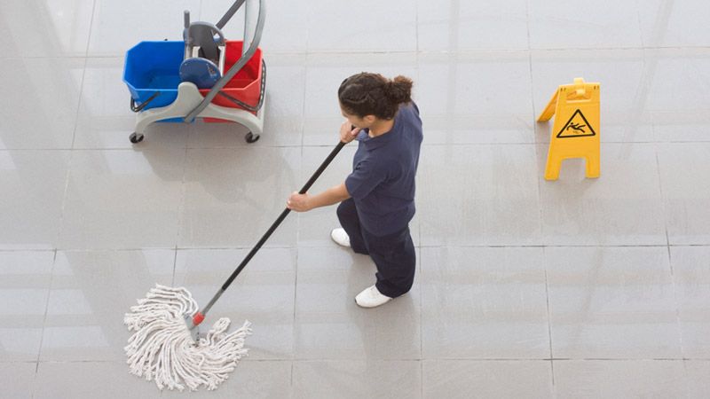Mujer limpiando piso de lobby
